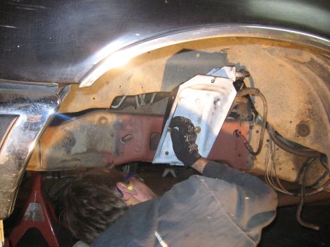 1989 Ford Bronco - Mechanic works on a vehicle's frame, likely performing repairs or modifications in the wheel well area.