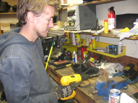 1989 Ford Bronco - A person works on a project at a cluttered workbench, surrounded by tools and supplies.