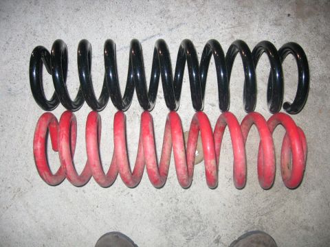 1989 Ford Bronco - Comparison of two coil springs, one black and one red, on a concrete floor.