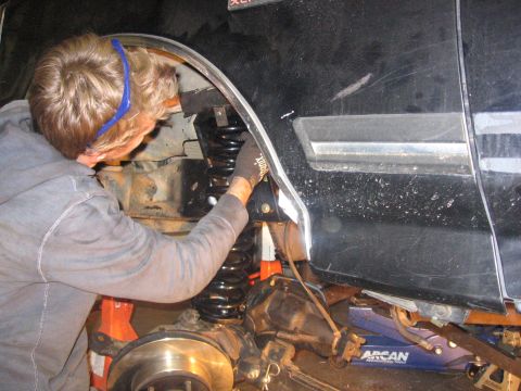 1989 Ford Bronco - A person is shown working on the suspension system of a vehicle, with the wheel assembly disassembled.