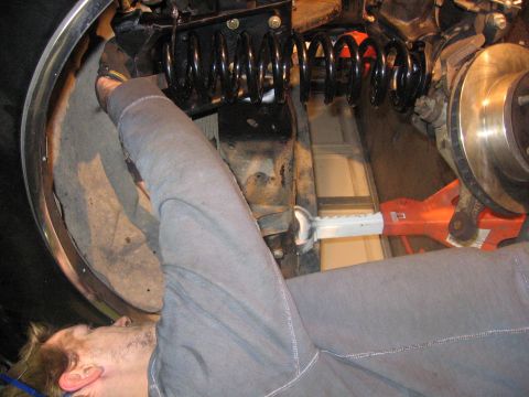 1989 Ford Bronco - A person works on the suspension and brake components of a vehicle, with a focus on the coil spring and rotor.