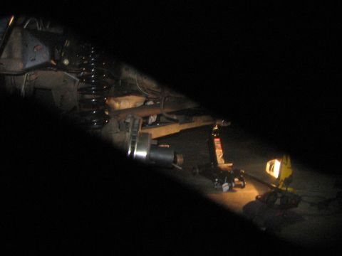 1989 Ford Bronco - Vehicle undercarriage repair in progress, illuminated by a work light.