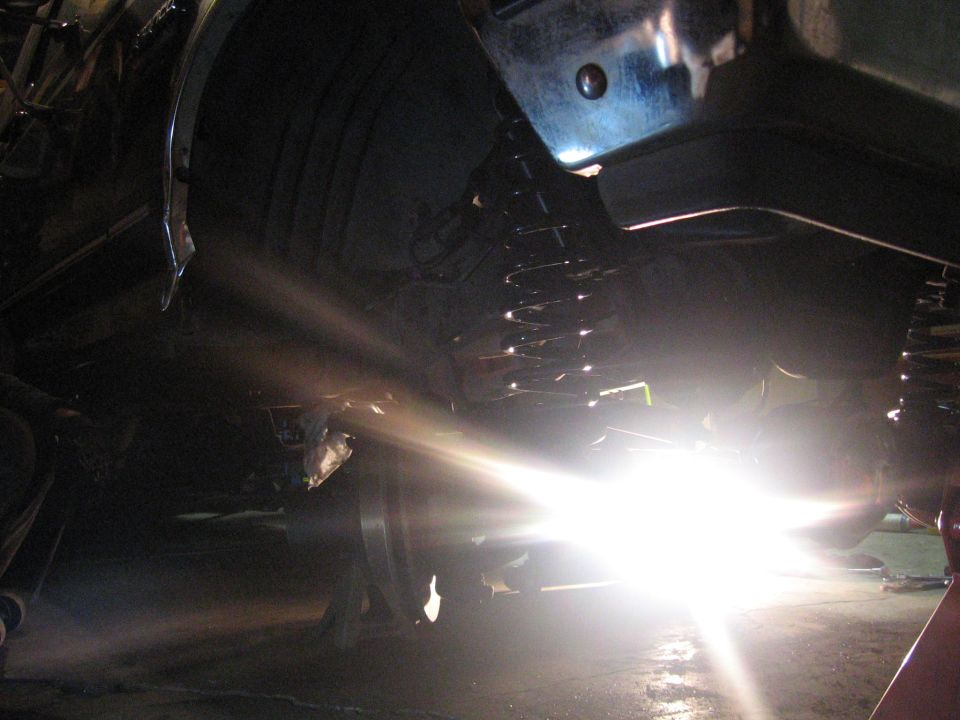 Undercarriage of a vehicle with a bright light shining on the suspension and tire