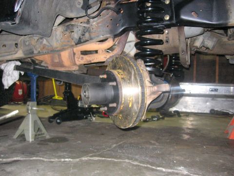 1989 Ford Bronco - Vehicle's front suspension and brake assembly undergoing maintenance, supported by jack stands.
