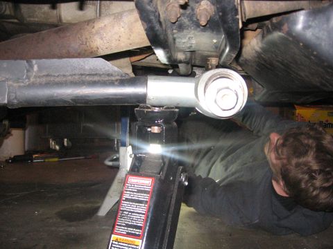1989 Ford Bronco - A person works on the underside of a vehicle, which is raised by a jack and jack stand.