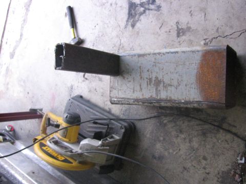 1989 Ford Bronco - A metal bracket is shown with a yellow DeWalt saw and a hammer on a concrete floor, suggesting a workshop or installation setting.