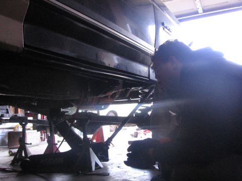 1989 Ford Bronco - A mechanic works on the suspension of a vehicle in a garage setting.