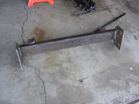 1989 Ford Bronco - A metal frame component rests on a cracked concrete surface, with a jack visible in the background.