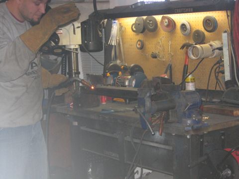 1989 Ford Bronco - A person is welding metal in a workshop setting, with tools and equipment visible in the background.