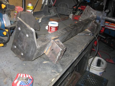 1989 Ford Bronco - A custom-fabricated metal component rests on a workbench, surrounded by tools and workshop supplies.