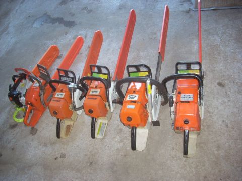 2000 Chevrolet Tahoe - A collection of Stihl chainsaws with orange bars and handles are displayed on a concrete surface.