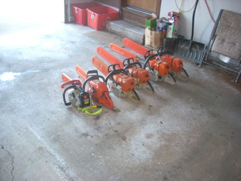 2000 Chevrolet Tahoe - A collection of chainsaws, some with orange handles and bars, are neatly arranged on a garage floor.