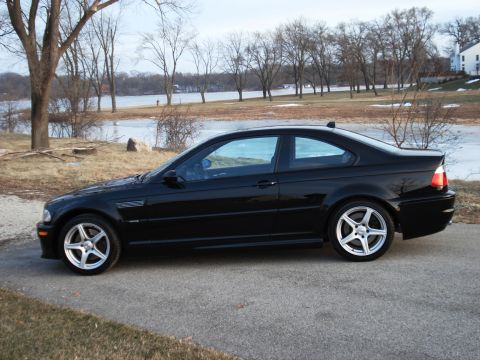 1998 Ford Taurus - A black BMW M3 coupe is seen from the side, parked outdoors with a lake in the background.