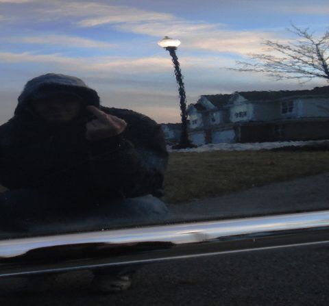 1998 Ford Taurus - Reflection of a person in a car door shows houses and a streetlamp under a cloudy sky.