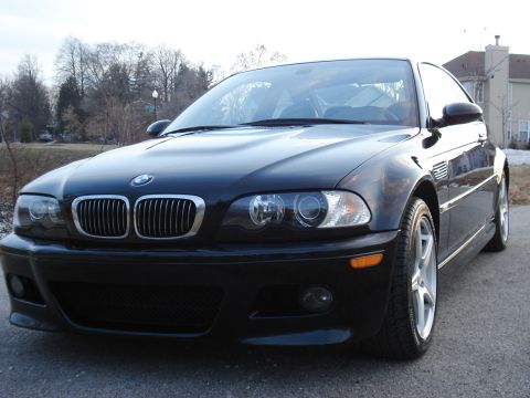 1998 Ford Taurus - A black BMW M3 is parked outside a house on a cloudy day.