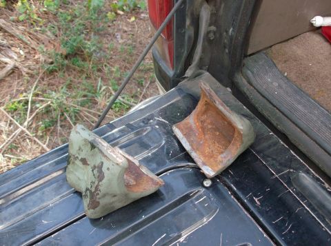 1989 Ford Bronco - Two rusty metal parts are placed in the bed of a truck.