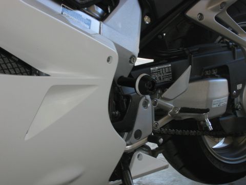 1985 Ford Crown Victoria LTD - Detail of a motorcycle's drivetrain and bodywork, showing the chain and part of the rear wheel.