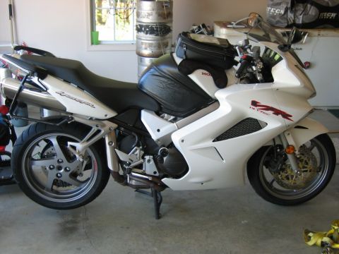 1985 Ford Crown Victoria LTD - A white Honda VFR motorcycle is parked indoors, showing its side profile and a black tank bag on the fuel tank.