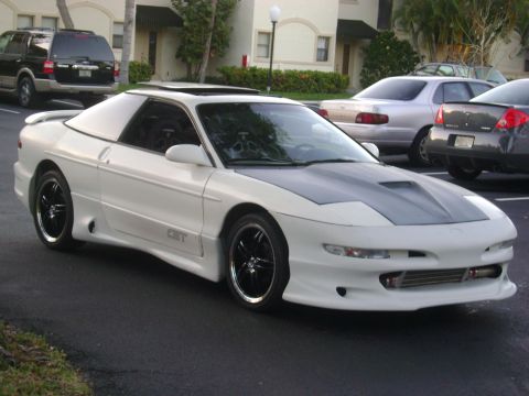 1994 Ford Probe - A white 1994 Ford Probe is parked outside a building, showing its custom hood and body kit.
