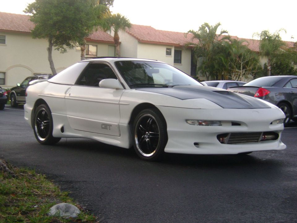 White Ford Probe with a custom hood and body kit, parked outside