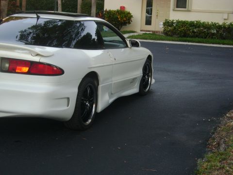 1994 Ford Probe - A white coupe with aftermarket wheels and a body kit is parked on a dark asphalt driveway.