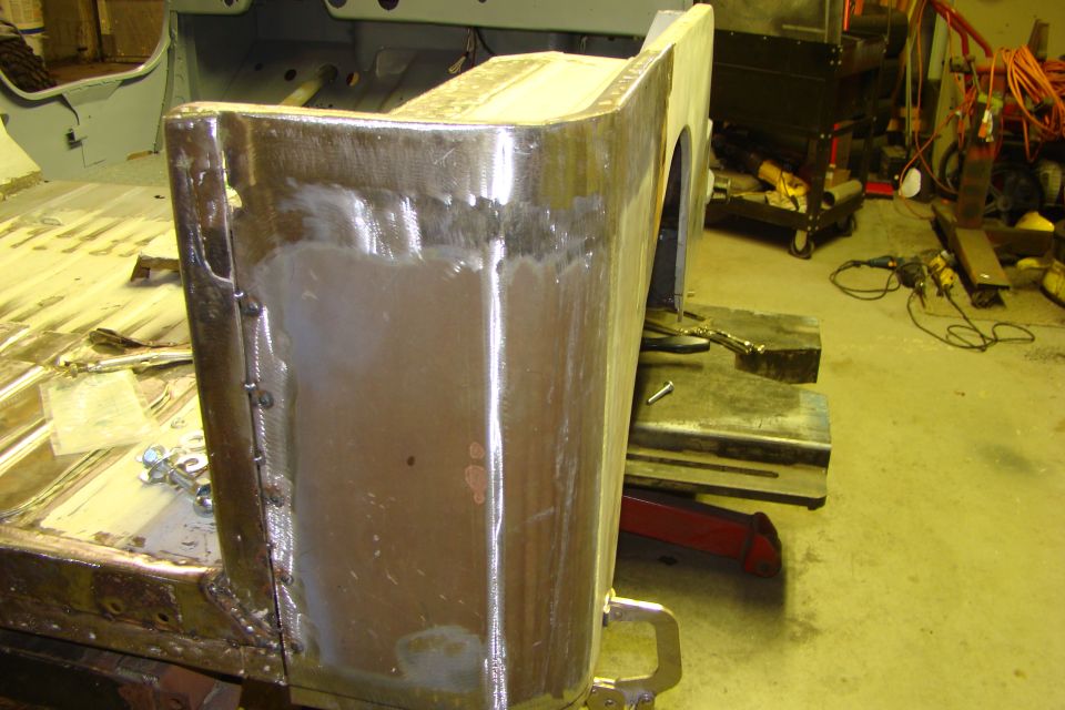 Close-up of a vehicle's rear quarter panel undergoing metal repair and welding