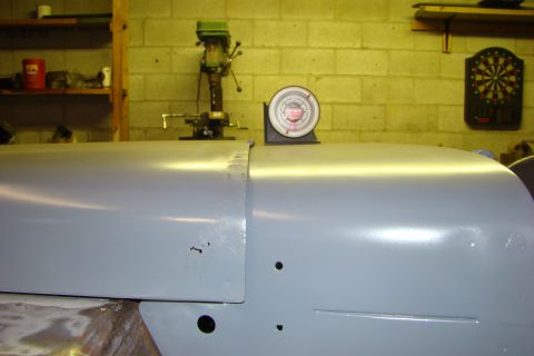 1948 Jeep Wrangler - A close-up of a vehicle's body panels, possibly undergoing restoration, with a gauge and workshop tools visible.
