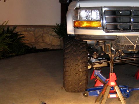 1996 Ford Bronco - Front suspension and tire of a 1996 Ford Bronco are supported by jack stands.