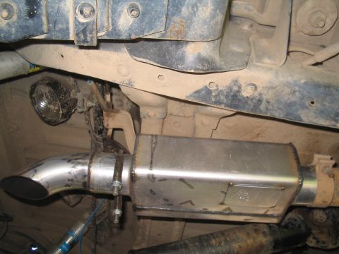 1989 Ford Bronco - Close-up of a vehicle's aftermarket exhaust system, a polished metal muffler and tailpipe.