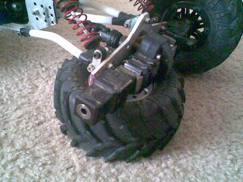 1984 Ford Bronco II - Close-up of RC crawler suspension and wheel assembly on carpet.