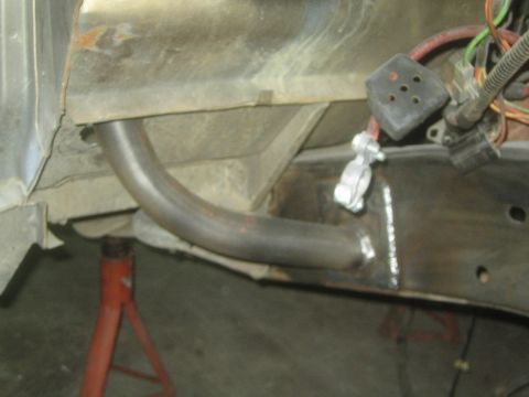 1990 Ford Bronco - bent tubular suspension link bolts to a welded chassis bracket under a vehicle supported on a red jack stand.
