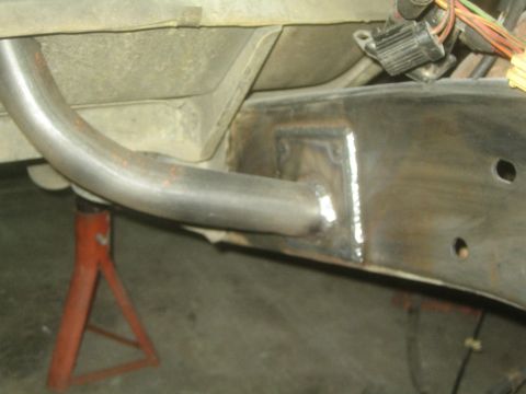 1990 Ford Bronco - curved tubular suspension link is welded to a gusseted chassis bracket on a vehicle raised on a jack stand.