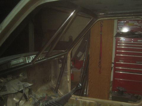 1990 Ford Bronco - interior of a truck cab under construction shows a fabricated roll cage, with a red tool chest in the background.