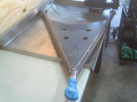 1990 Ford Bronco - Photograph of a fabricated steel suspension bracket with drilled lightening holes on a workbench.