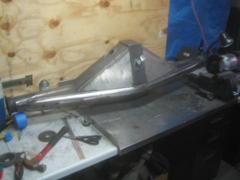 1990 Ford Bronco - Photograph of a fabricated tubular off-road suspension arm on a workbench surrounded by hand tools.