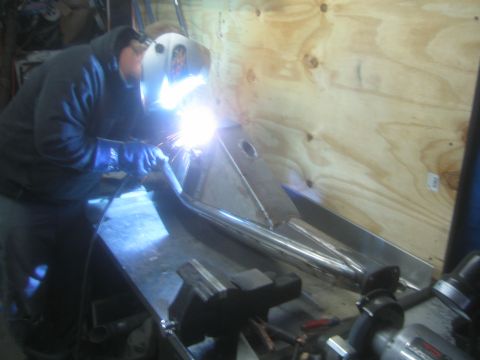 1990 Ford Bronco - Photograph of a welder joining a fabricated tubular suspension arm with an arc-welding flash visible.