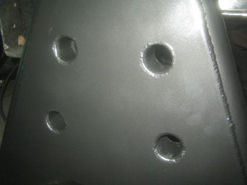 1990 Ford Bronco - Photograph of drilled lightening holes and a weld seam in a fabricated steel bracket plate.