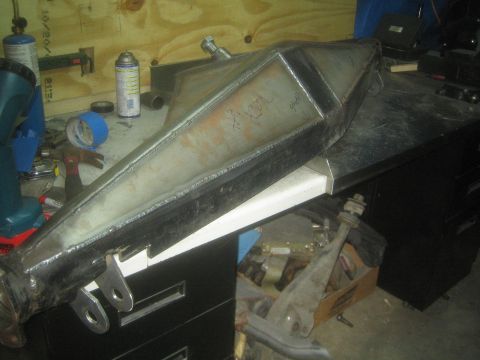 1990 Ford Bronco - Photograph of a fabricated boxed-steel off-road suspension arm with weld tabs on a shop workbench.
