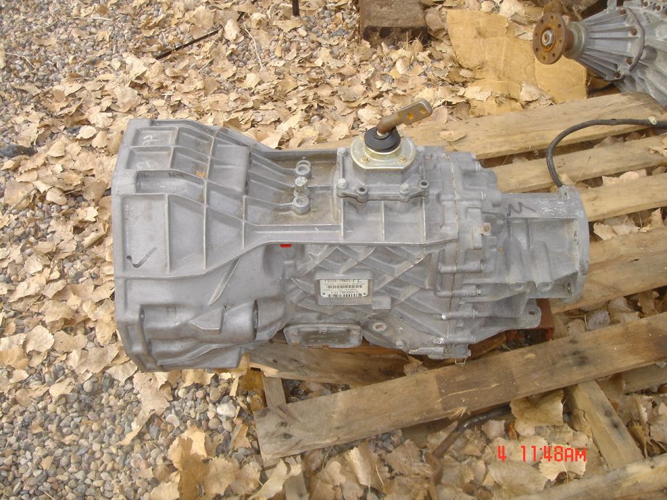 Aluminum manual transmission with shifter stub lying on wooden pallets outdoors