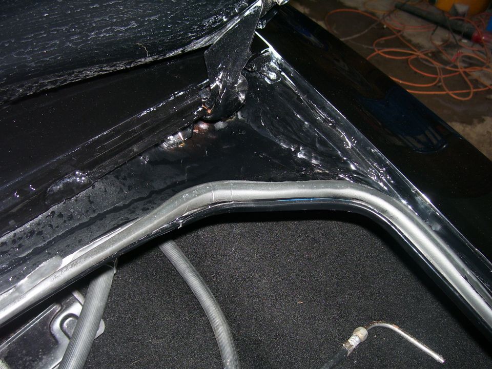 Close-up of black car interior trunk edge with rubber seal and carpeting.