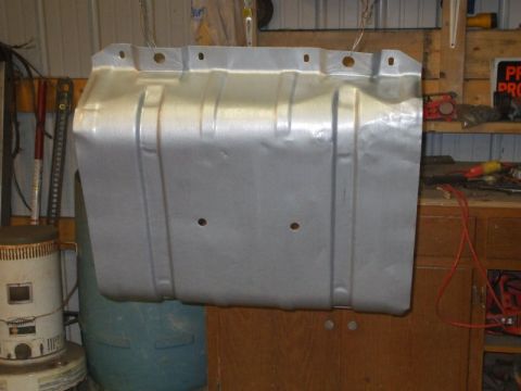 1995 Ford Bronco - A stamped-steel skid plate or transmission crossmember shield hanging by wires in a workshop after being stripped and sprayed in silver pai…