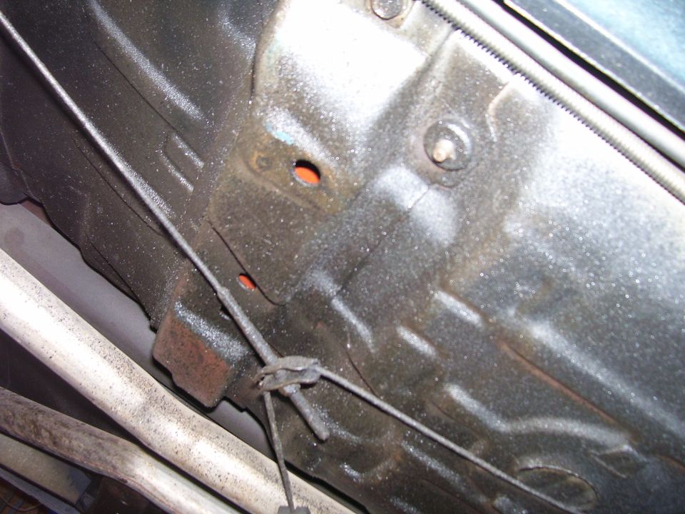 Underside of a vehicle chassis with exhaust pipes and a cable.