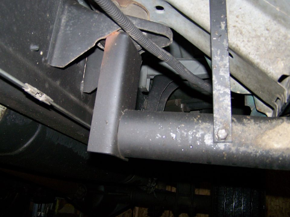 Underside of a vehicle showing exhaust pipe and bracket.