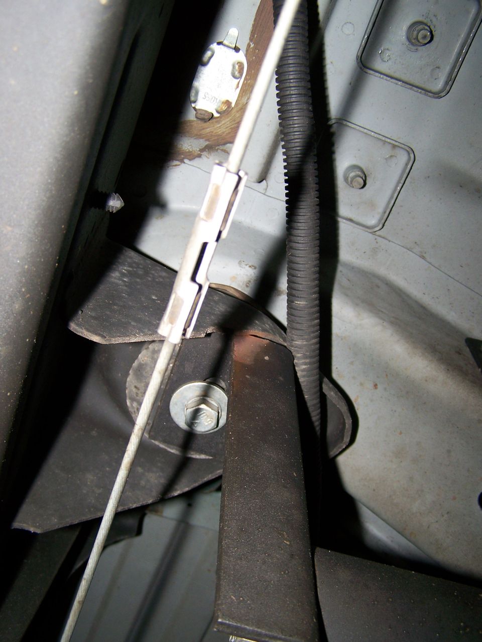 Undercarriage view of a vehicle showing a cable and bracket assembly.