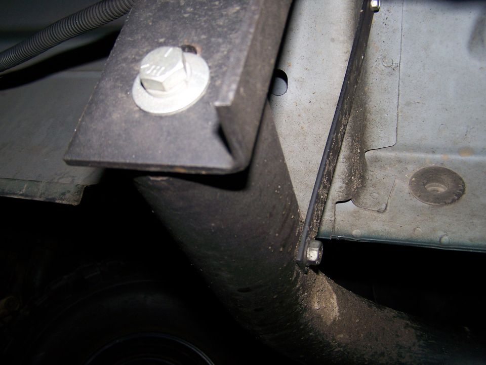 Underside of a vehicle showing a black metal bracket bolted to the frame.