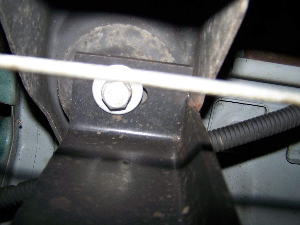 Close-up of a bolt and bracket on a vehicle, with a black hose.