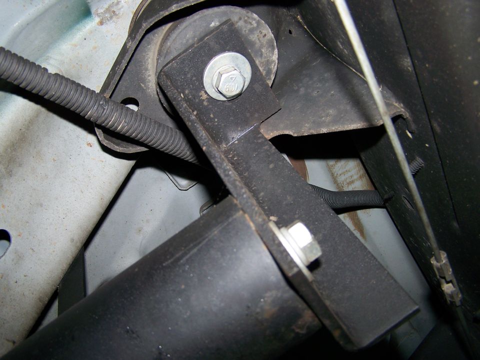 Vehicle suspension bracket attached to shock absorber with bolt and nut, wire loom visible.