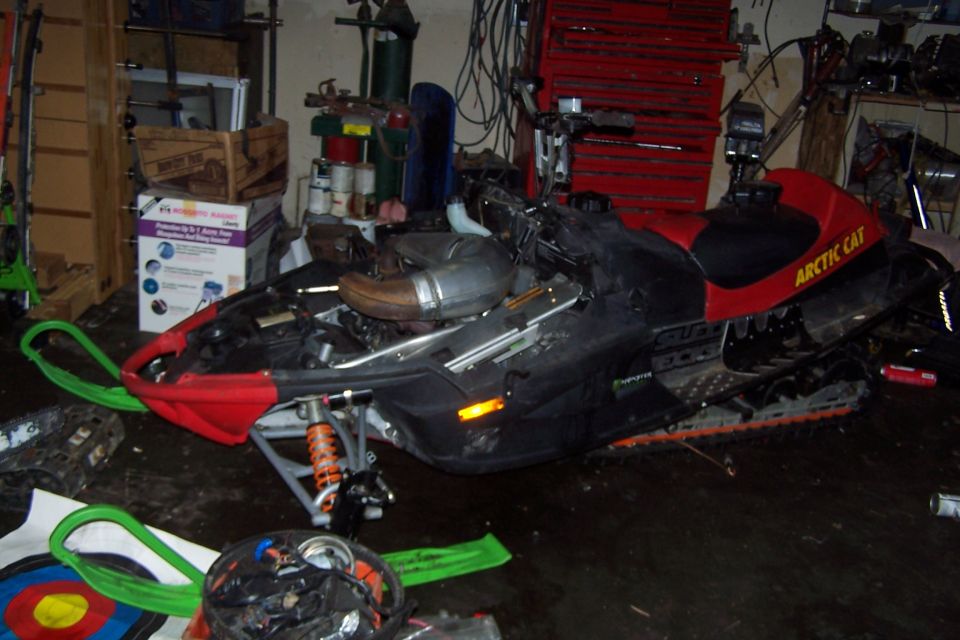 Arctic Cat snowmobile in a garage, partially disassembled.