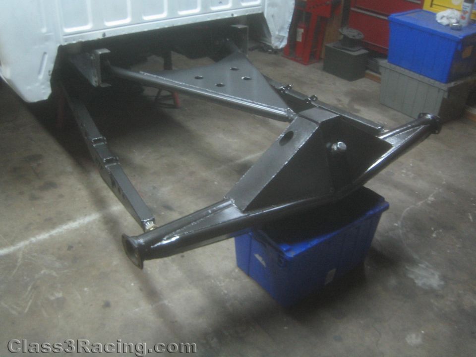 Fabricated black tubular suspension assembly under a vehicle in a shop
