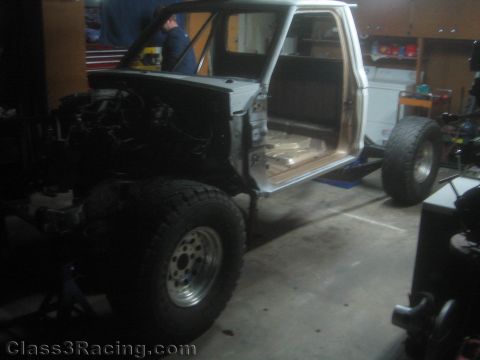 1990 Ford Bronco - Photograph of a pickup truck cab on stands during an off-road suspension build in a home garage.